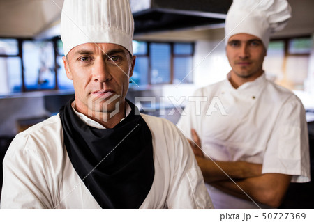 Two male chefs standing with arms crossed in kitchen Two male chefs standing with arms crossed in kitchen 50727369