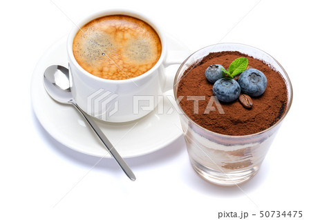 Classic tiramisu dessert with blueberries in a glass and cup of coffee isolated on a white Classic tiramisu dessert with blueberries in a glass and cup of coffee isolated on a white 50734475