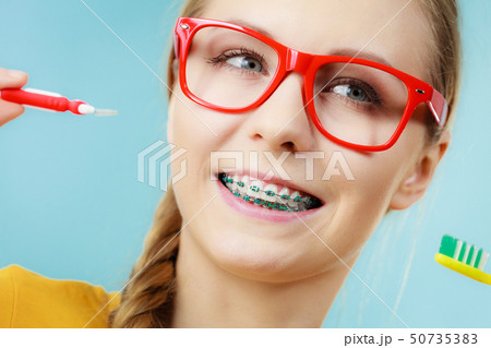 Girl with teeth braces using interdental and 50735383