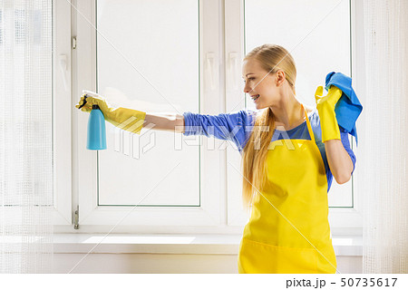 Woman cleaning window at home 50735617