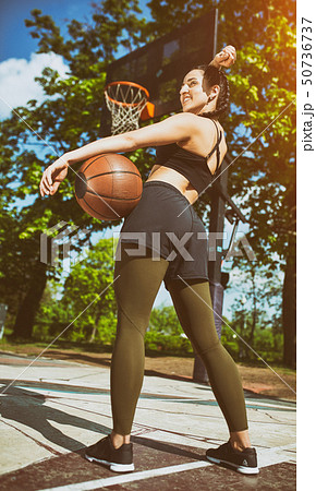 Beautiful sexy fitness girl in black sport wear with perfect body with basket ball at basketball Beautiful sexy fitness girl in black sport wear with perfect body with basket ball at basketball 50736737