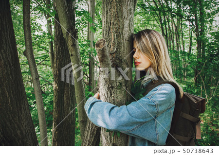 woman with backpack hugging a tree in forest  50738643
