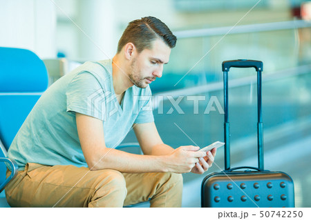 Young man in an airport lounge waiting for flight aircraft. 50742250