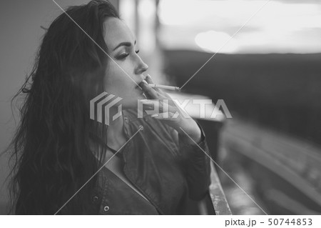 Young woman holding a cigarette and smoking. Young woman holding a cigarette and smoking. 50744853
