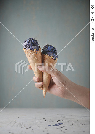 hand holding waffle cone with purple ice cream 50744934