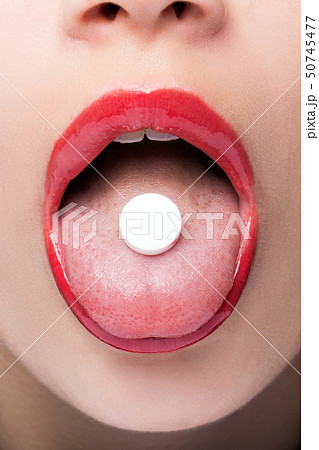 White round tablet in the language of the girl close-up 50745477