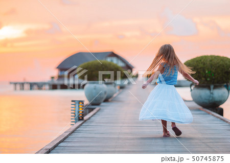 Silhouette of adorable little girl on wooden jetty at sunset 50745875