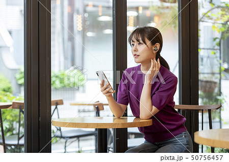 ワイヤレスヘッドホンをしてスマホを操作する女性 50756457