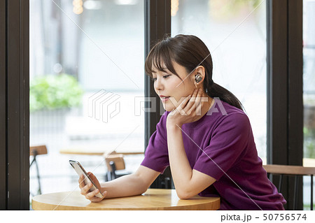 ワイヤレスヘッドホンを付けてスマホを持つ女性 50756574