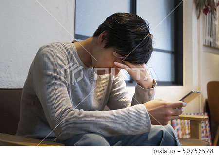 スマートフォンを手に考え込む男性 スマートフォンを手に考え込む男性 50756578