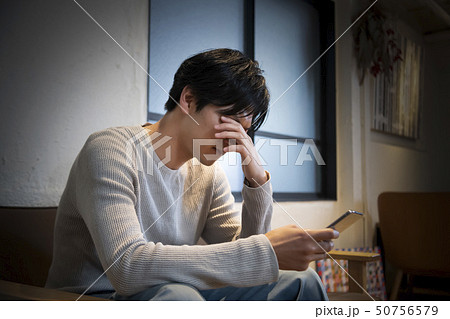 スマートフォンを手に考え込む男性 スマートフォンを手に考え込む男性 50756579