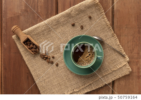 A cup of black coffee with roasted coffee beans, shot from the top on a dark rustic wooden 50759164