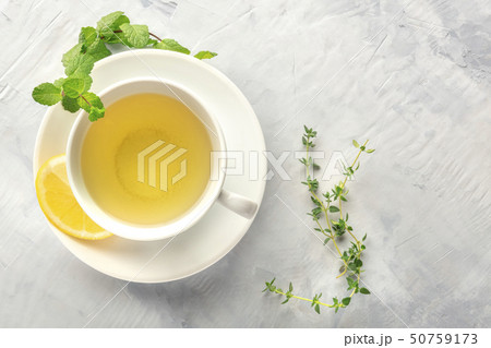 A cup of green tea with lemon, shot from above with mint, thyme, and copy space 50759173
