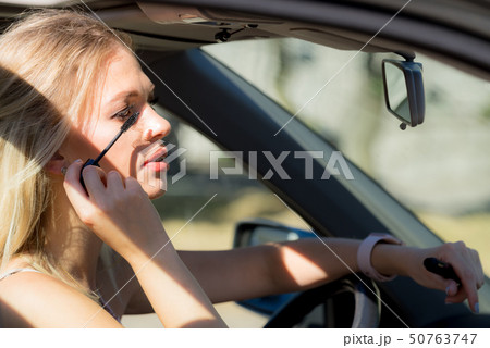 Woman applying mascara in car Woman applying mascara in car 50763747