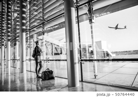 Young woman waiting at airport, looking through the gate window. 50764440