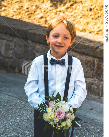 Ring bearer at garden wedding playing with bouquet Ring bearer at garden wedding playing with bouquet 50765040