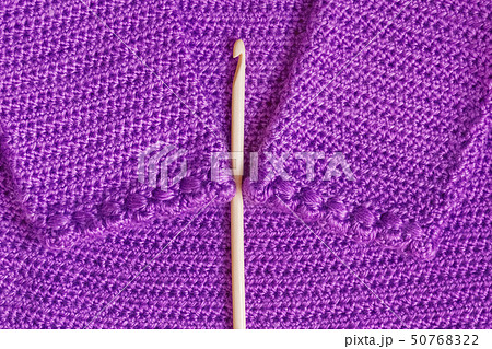 Baby purple cardigan, crocheted close-up and wooden hook 50768322
