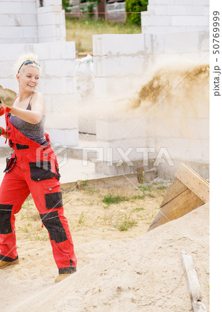 Woman using shovel on constriction site 50769999