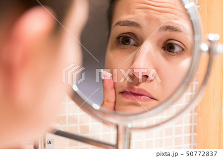 Young girl in front of a bathroom mirror putting Young girl in front of a bathroom mirror putting 50772837