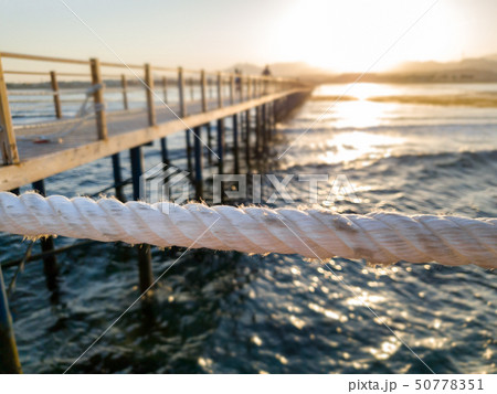 Beautiful view on sunset over the ocean, mountain and long wooden pier 50778351