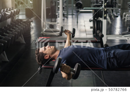 Handsome weightlifter lifting bench press working Handsome weightlifter lifting bench press working 50782766