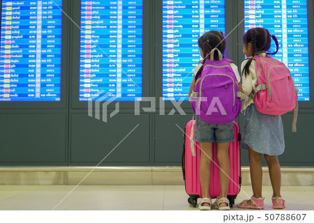 Two asian girl with backpack checking their flight Two asian girl with backpack checking their flight 50788607