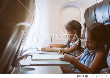 Two cute asian child girls traveling by airplane Two cute asian child girls traveling by airplane 50788609