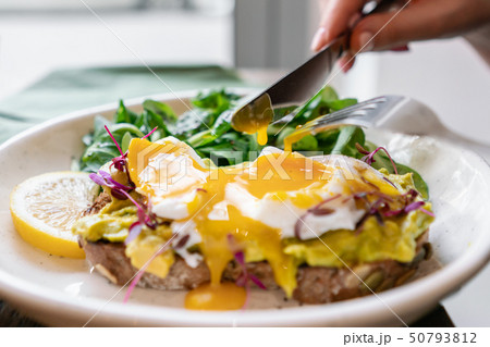 Young woman eat breakfast with knife and fork, Morning in cafe. Healthy breakfast with wholemeal 50793812