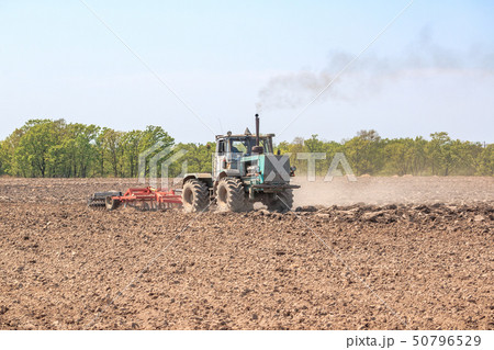 The tractor plows the soil. The tractor plows the soil. 50796529