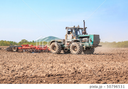 The tractor plows the soil. 50796531