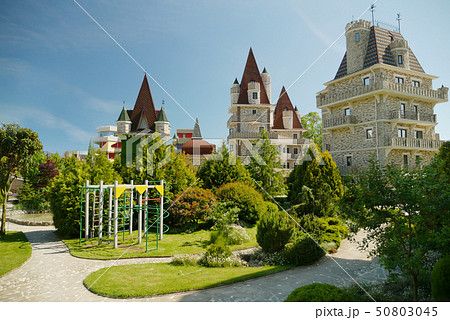 modern Victorian-style luxury hotel with a small children's play area at the foot, against a blue 50803045