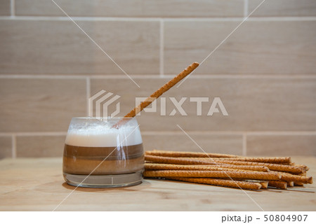 multilayer coffee or cappuccino in a glass cup with bread straw 50804907