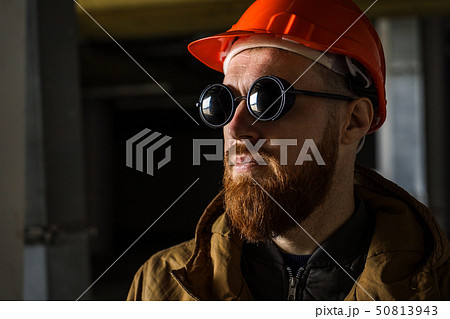 Man in a helmet and sunglasses in a dark room, looks away Man in a helmet and sunglasses in a dark room, looks away 50813943