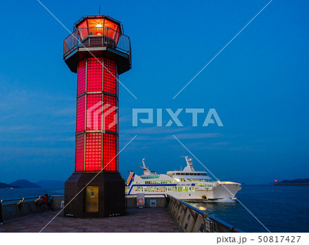 高松港の赤灯台、赤いガラス灯台「せとしるべ」前を航行するフェリー 50817427