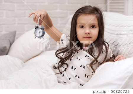 little child girl in pyjamas with clock 50820722