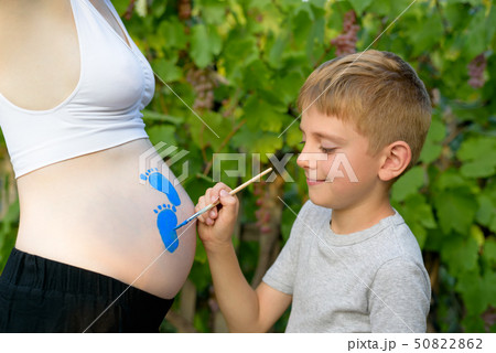 Little boy draws with a brush on the belly of his Little boy draws with a brush on the belly of his 50822862