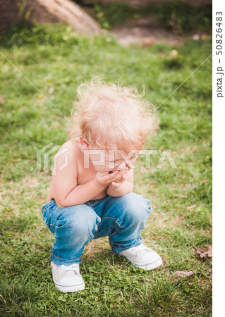 Cute little boy at summer day on green lawn 50826483
