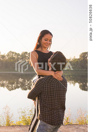 Romantic, people and summer concept - man raised a woman in his arms near the lake at the sunset 50826636