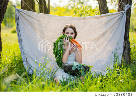 woman with vegetables sits near the trees 50830403