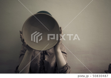 Potter holds round clay plate in his hands. 50830487