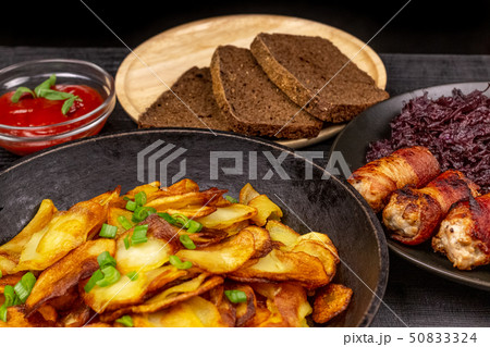 Roasted potato in the pot, pieces of rye black 50833324