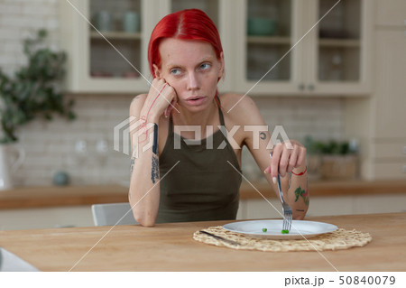 Skinny woman with bulimia eating only three green peas 50840079