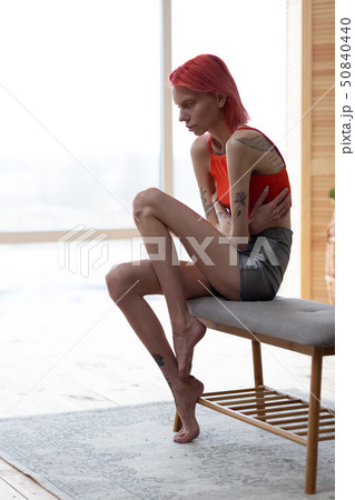 Skinny anorexic woman with long legs sitting near the window Skinny anorexic woman with long legs sitting near the window 50840440