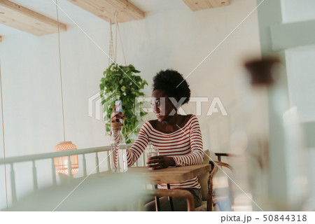 Low angle of happy African woman having rest in cafe Low angle of happy African woman having rest in cafe 50844318