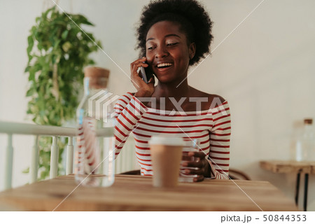 Low angle of happy African woman having rest in cafe Low angle of happy African woman having rest in cafe 50844353