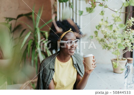 Waist up of smiling African lady drinking coffee in cafe Waist up of smiling African lady drinking coffee in cafe 50844533