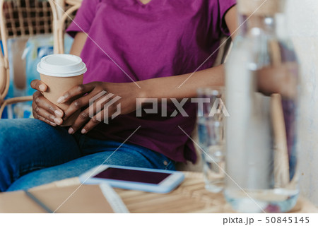 Close up of American lady keeping cupholder in arms at the cafe Close up of American lady keeping cupholder in arms at the cafe 50845145
