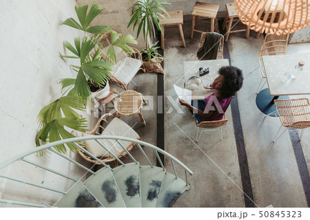 High angle of African woman with curly hair situating in cafeteria High angle of African woman with curly hair situating in cafeteria 50845323
