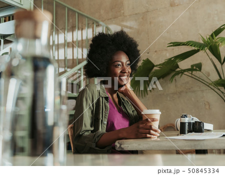Waist up of happy young African woman having rest in cafeteria 50845334