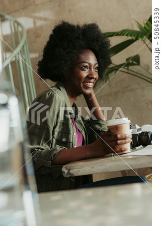 Waist up of cheerful young African woman having rest in cafeteria Waist up of cheerful young African woman having rest in cafeteria 50845339